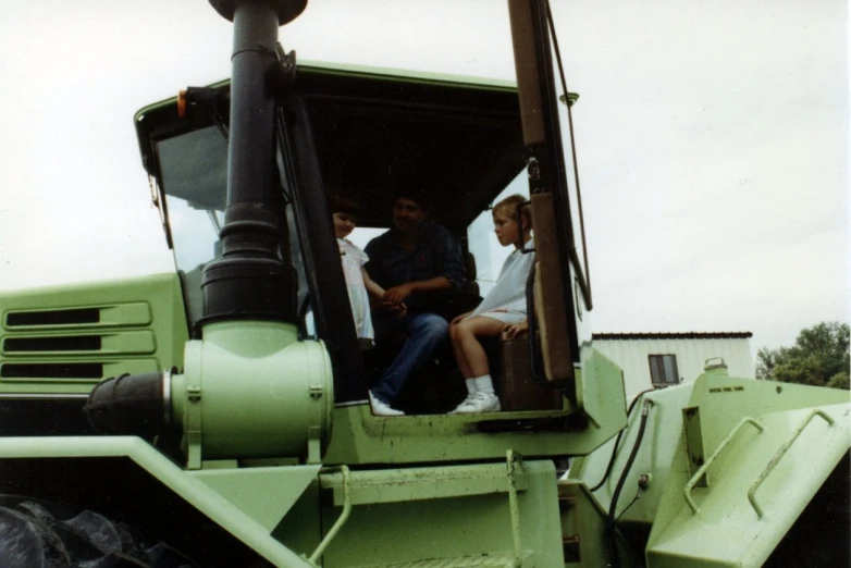 two people on a farm tractor sitting next to one another