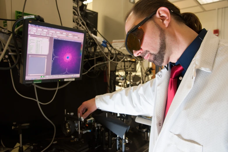 a man in a lab coat with a computer monitor