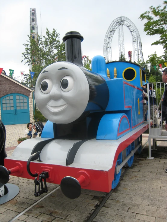 a blue, red and white thomas the tank is shown in front of the building