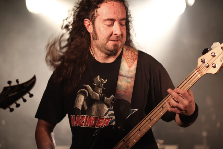 a man with long hair is playing guitar on a stage