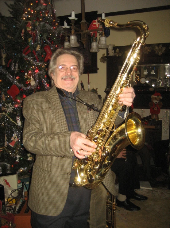 a man holding a saxophone next to a christmas tree