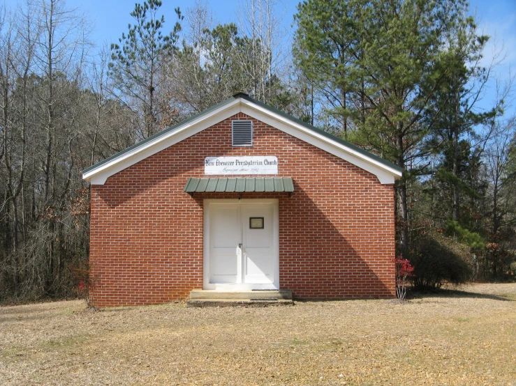 a small red brick building with a white door