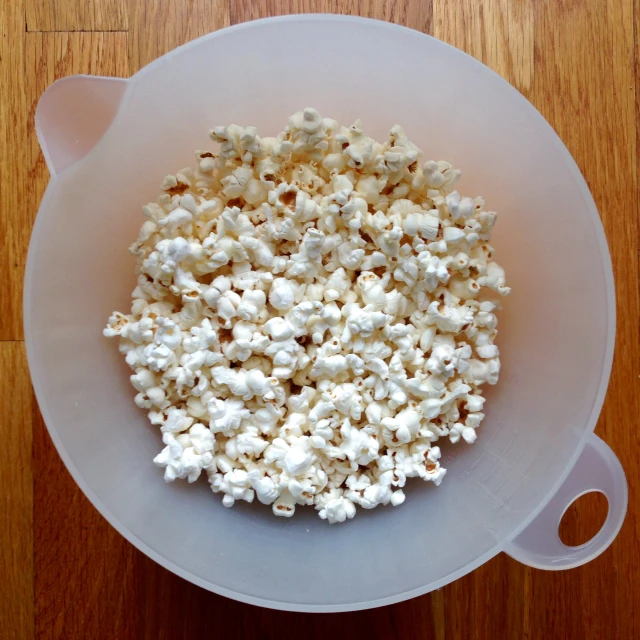 a big bowl full of popcorn sitting on the floor