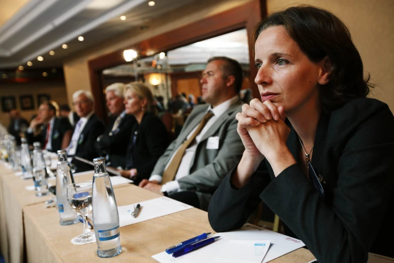 people in business suits are sitting at a long table