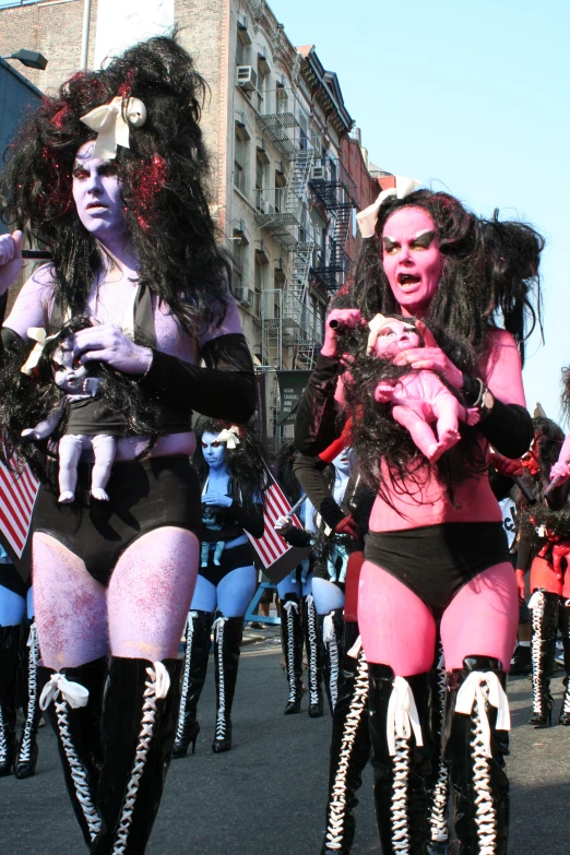 three female performers in colorful costume on a city street