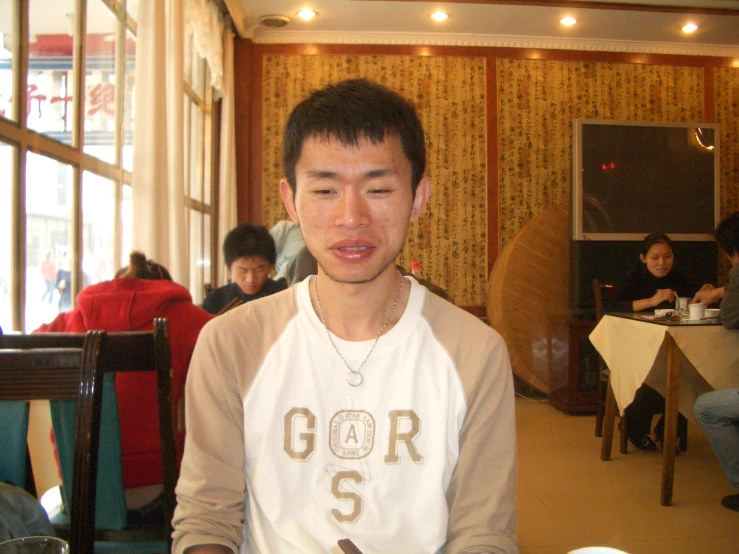 an asian man holding soing while sitting down