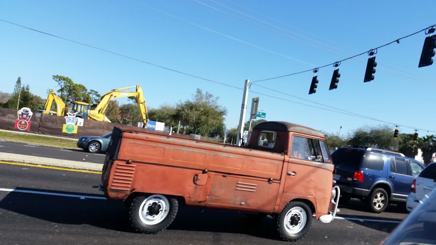 old rusty truck driving down a street next to traffic lights