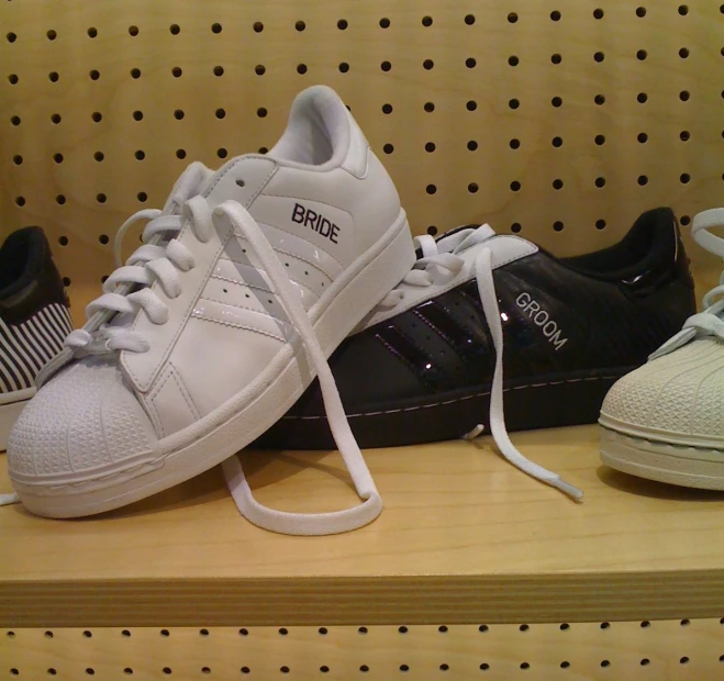 three white sneakers are sitting on a bench