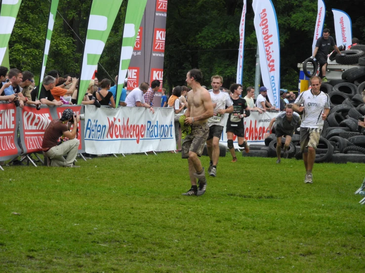 some people running together in the grass and people standing around