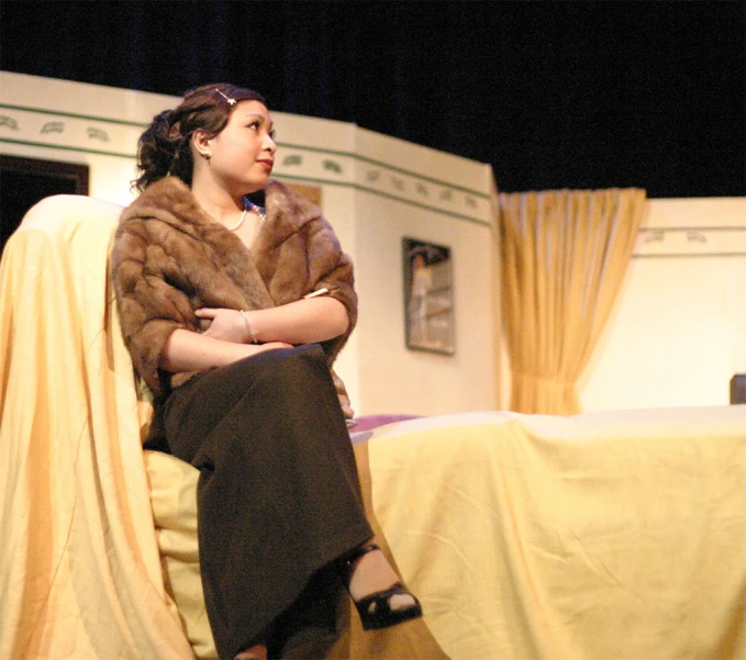 a woman in brown and tan furs sitting on a chair