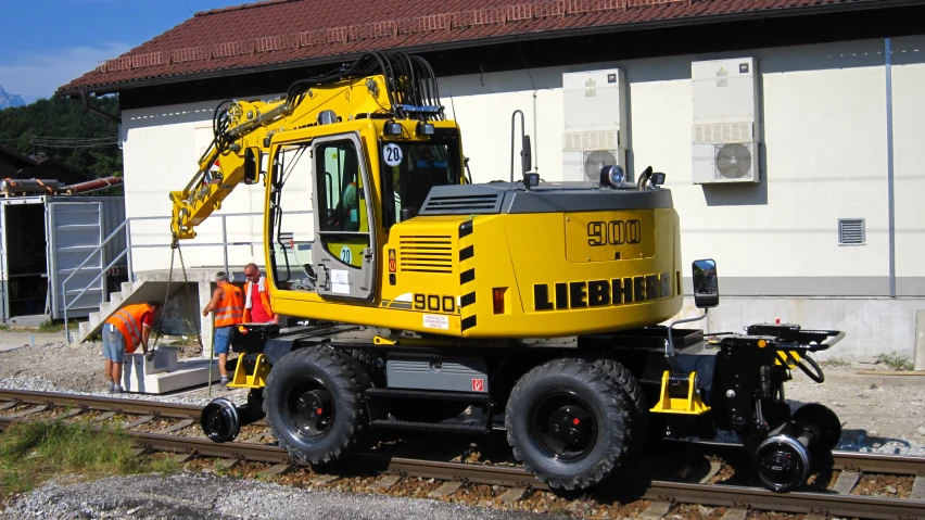 a yellow bulldozer on the tracks by a building