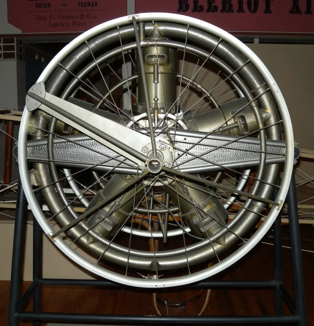a silver wheel sitting on top of a stand next to a wall
