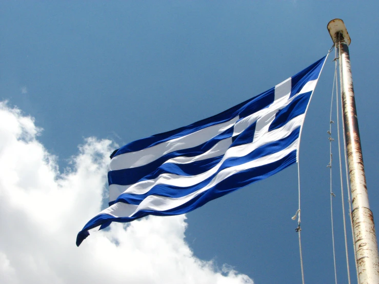 a blue and white flag is flown against the blue sky