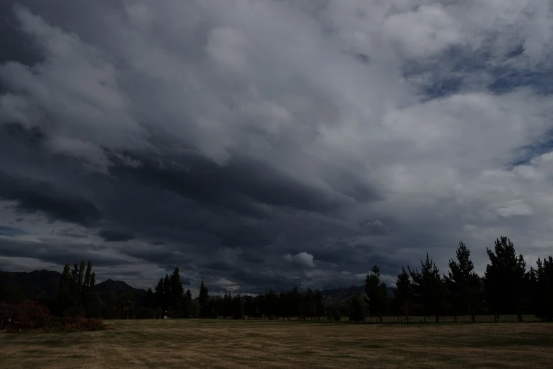 a very cloudy sky is shown above an open field