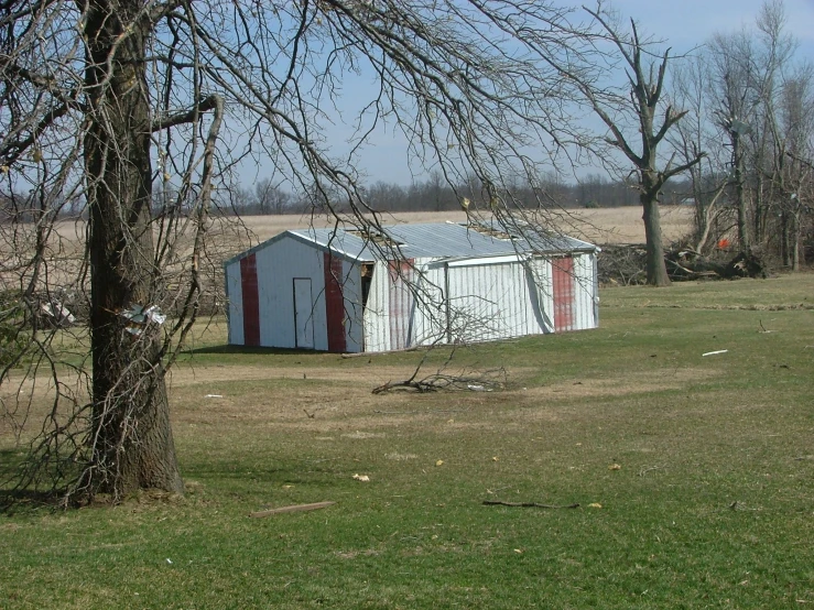 an outhouse in the middle of a large grassy field