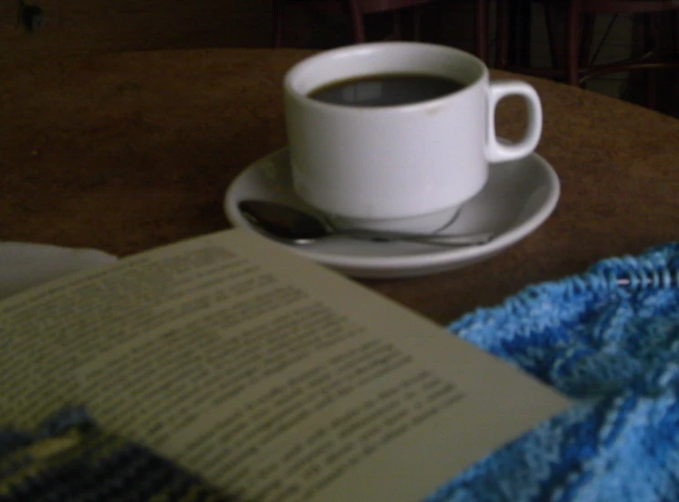 a book open and sitting on a table next to a cup of coffee