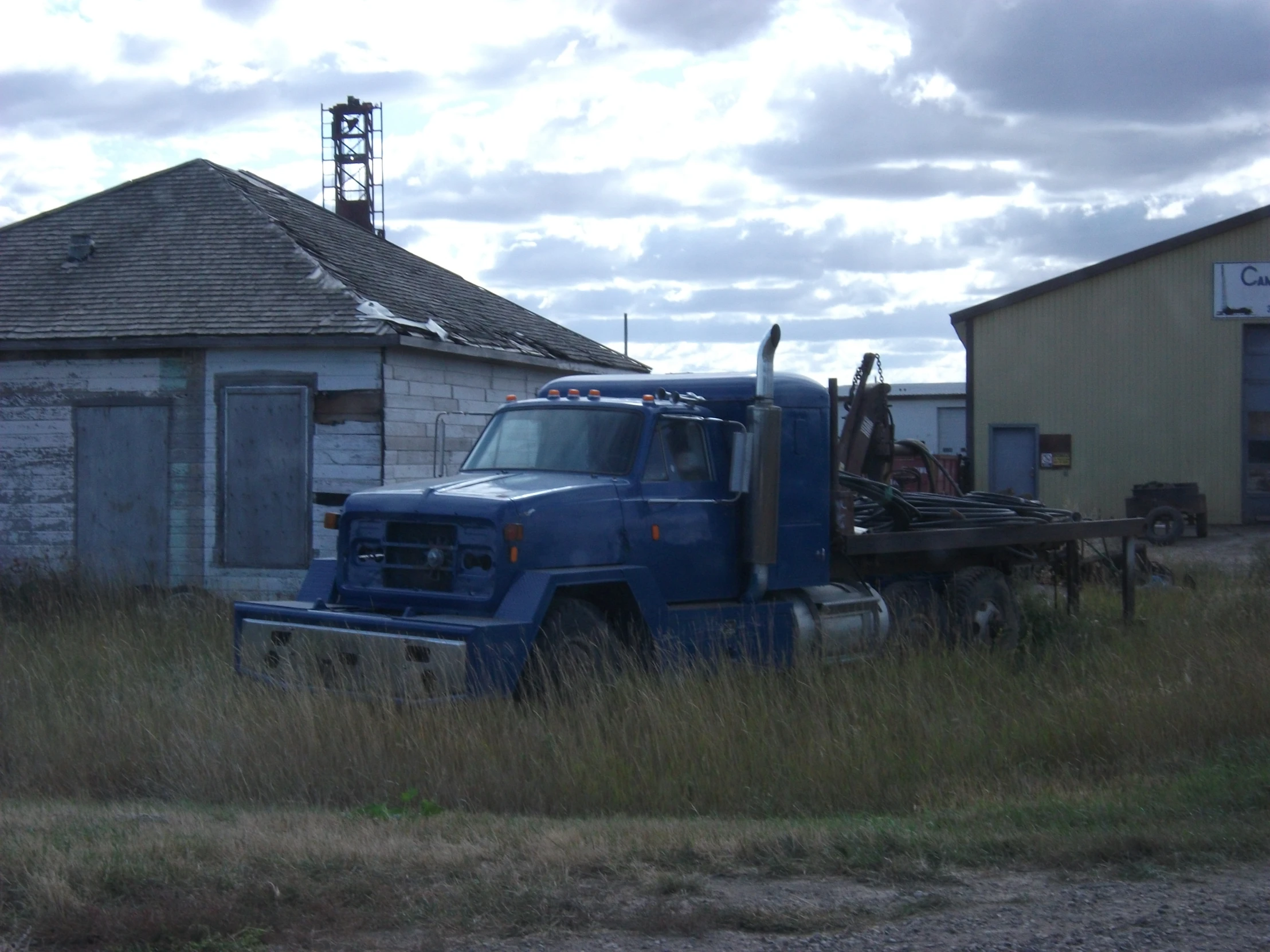 a truck parked outside an abandoned building on a cloudy day