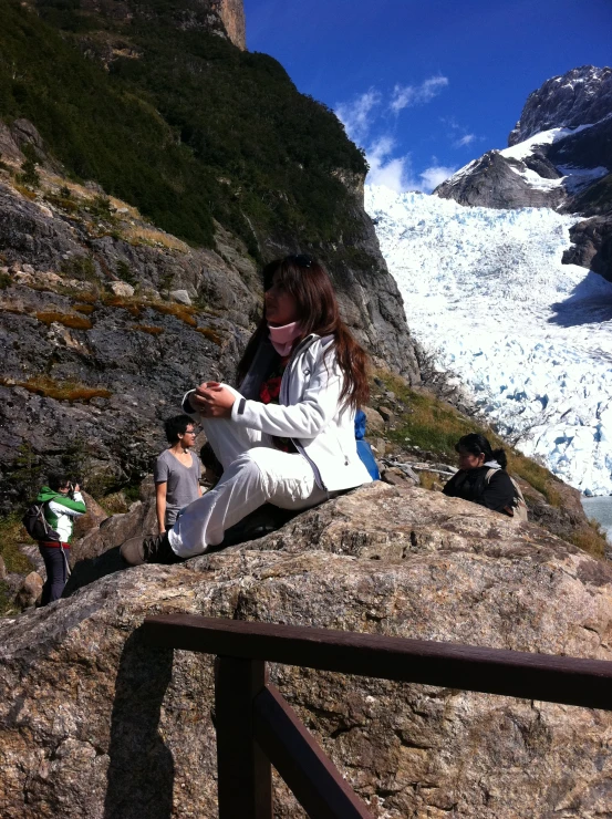 a woman sitting on a rock looking at her cell phone