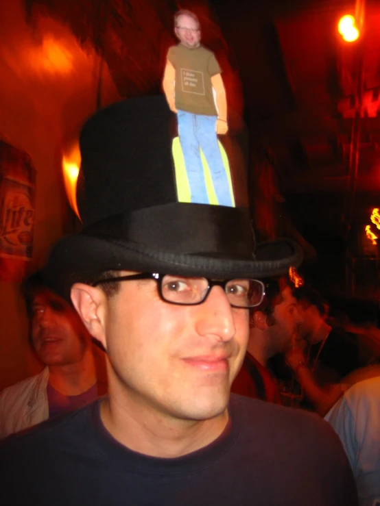 a man with glasses and a black hat has a piece of paper on top of his head