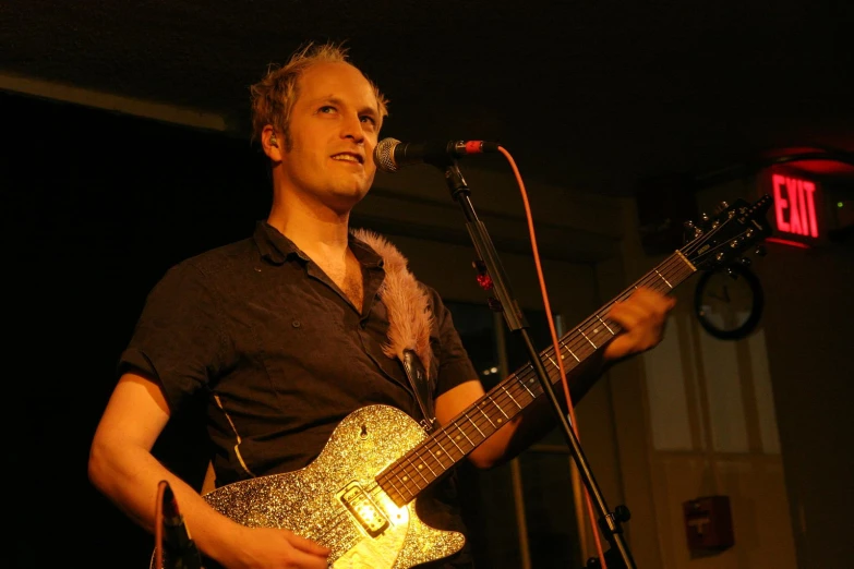 a man holding a guitar on top of a stage