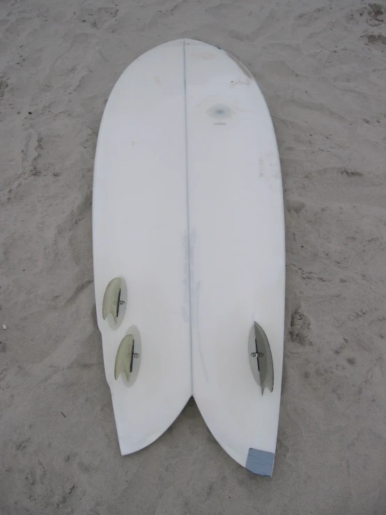 two white surfboards sitting on the beach sand