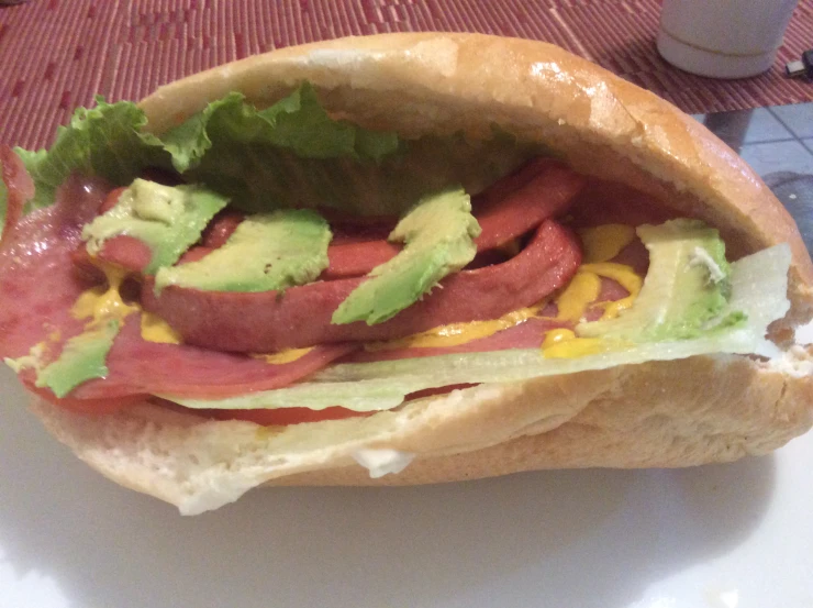 a meat and lettuce sub sandwich on a white plate