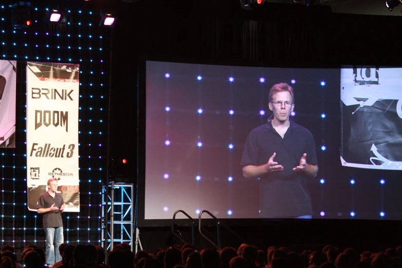 a person in glasses speaking on stage