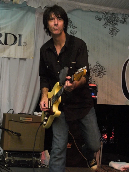 a person holding a guitar while standing in front of a speaker