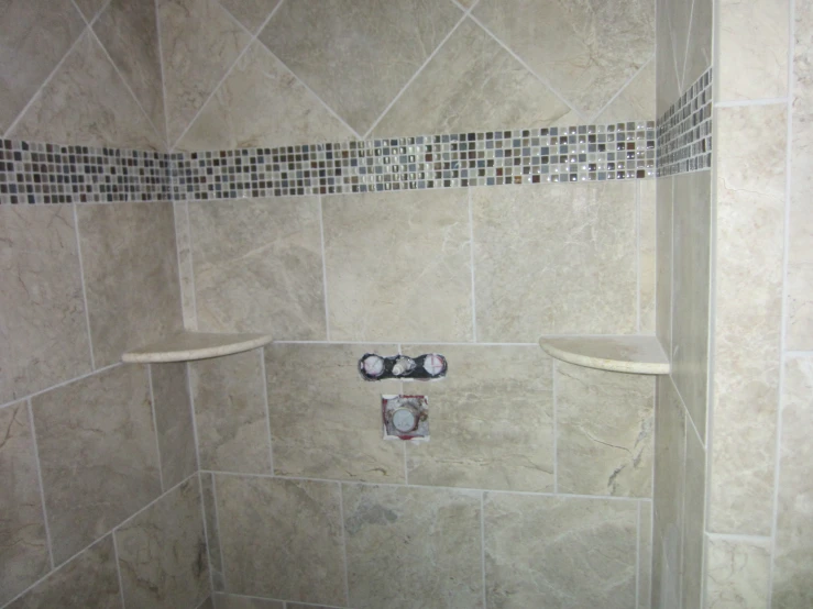 a marble tiled bathroom with the shower area with a towel bar and black and white tiled tiles