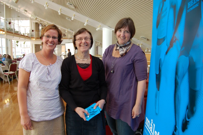 three women are standing next to a large poster