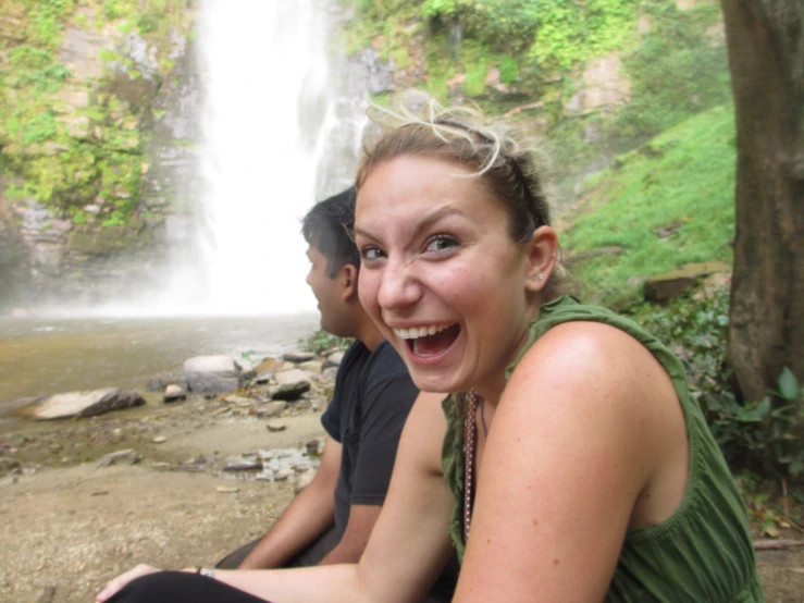 a woman taking a selfie next to a waterfall