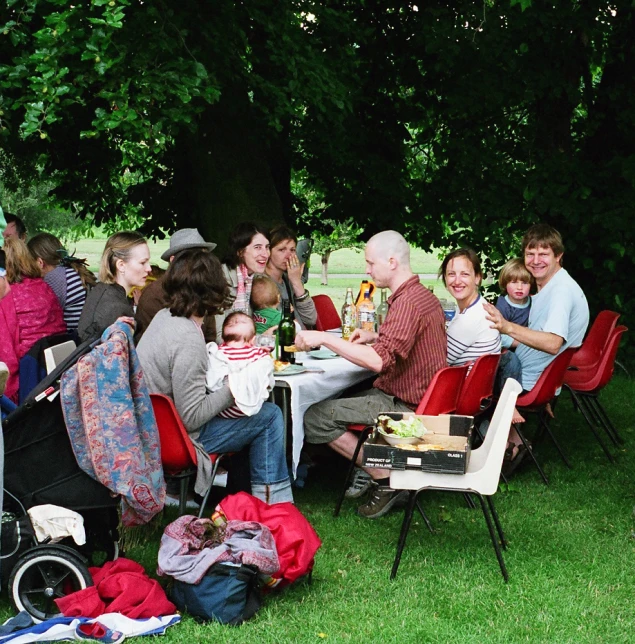 a group of people gathered outside in the grass eating and drinking