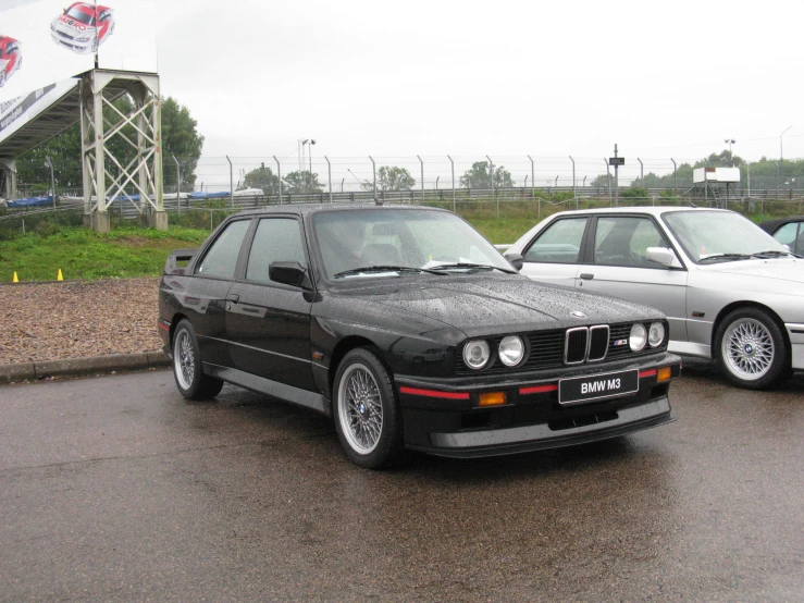 two bmws are parked in front of some metal barriers