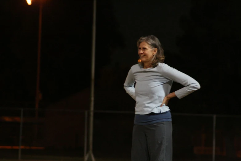 an old woman is standing and smiling with her hands on her hips