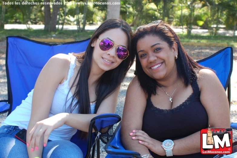 two women smiling and sitting in a chair