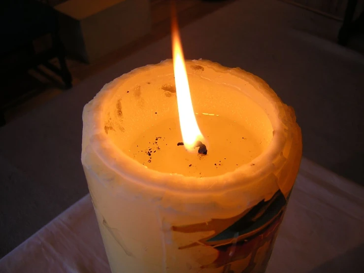 a yellow lit candle in the dark