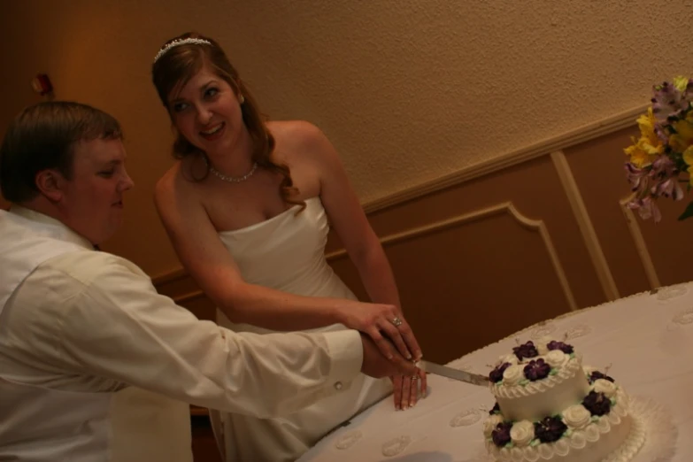 a bride and groom are  their wedding cake