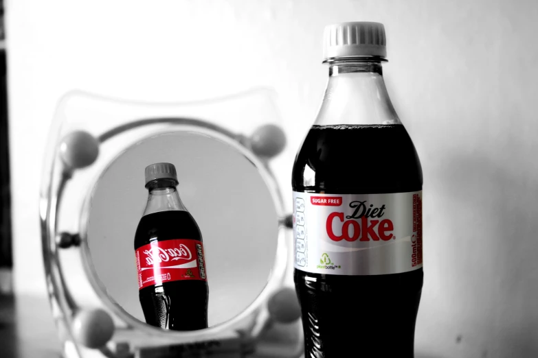a coke bottle is next to a mirror with a small hole on it