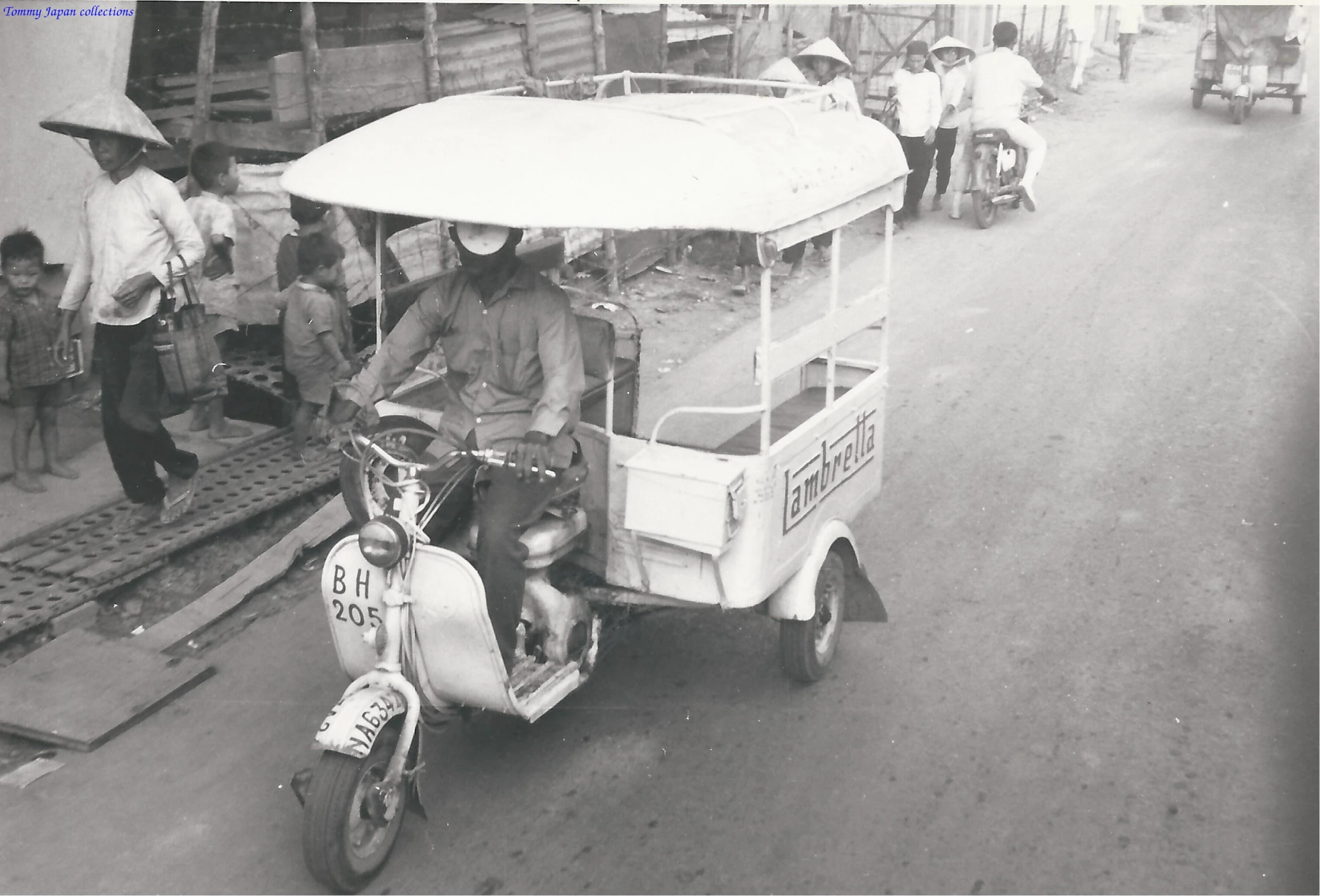 a small white cart with two people and a man on the back