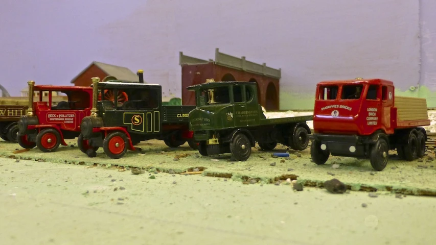 three red trucks and one green truck on a white floor