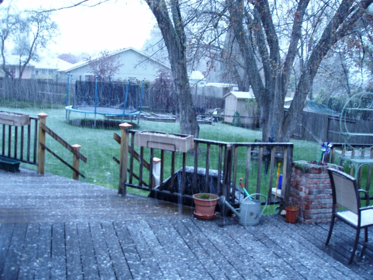 patio with chairs, plants and gardening equipment in the rain