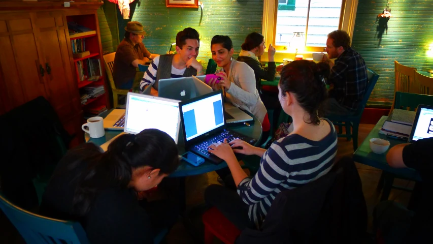 people with laptop computers in a classroom with books