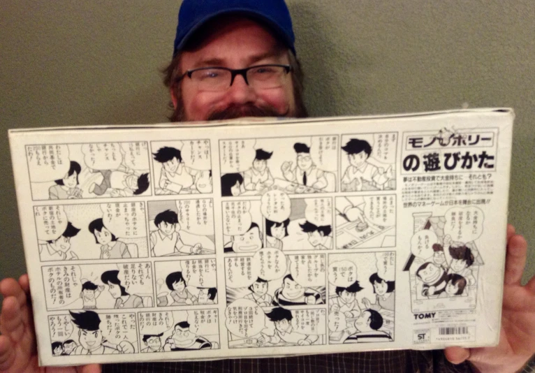 man with glasses holding up comic book that is about anime