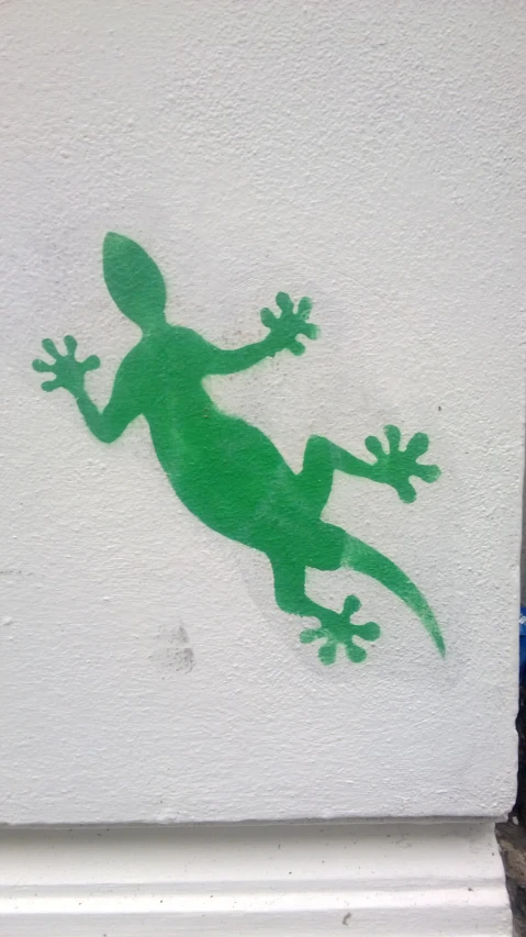 a green lizard on the side of a white wall