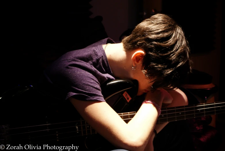 a person sitting in a chair with their head on a guitar