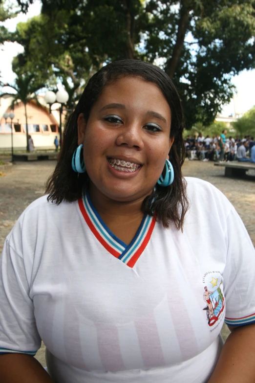 a woman with earrings and a shirt on smiles at the camera