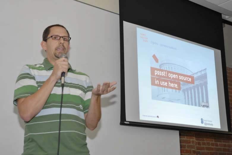 man holding up microphone standing in front of a projection screen