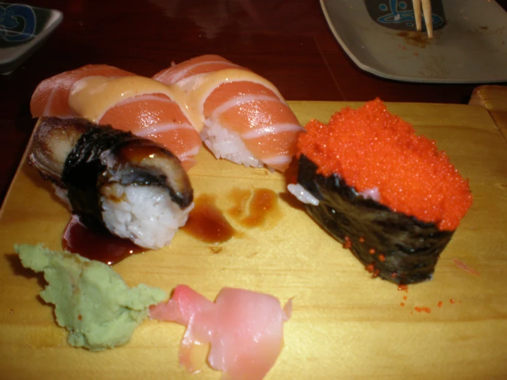 sushi with sauces on it sitting on top of a wooden  board