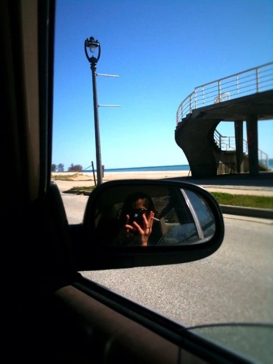 a woman is seen in the side mirror of a car