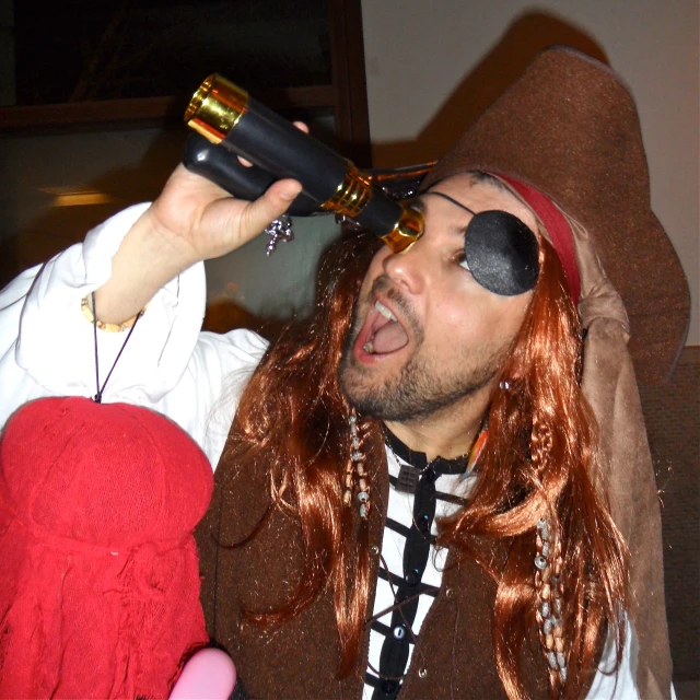 a man with a pirate eye patch on is holding his head down and drinking from a wine glass